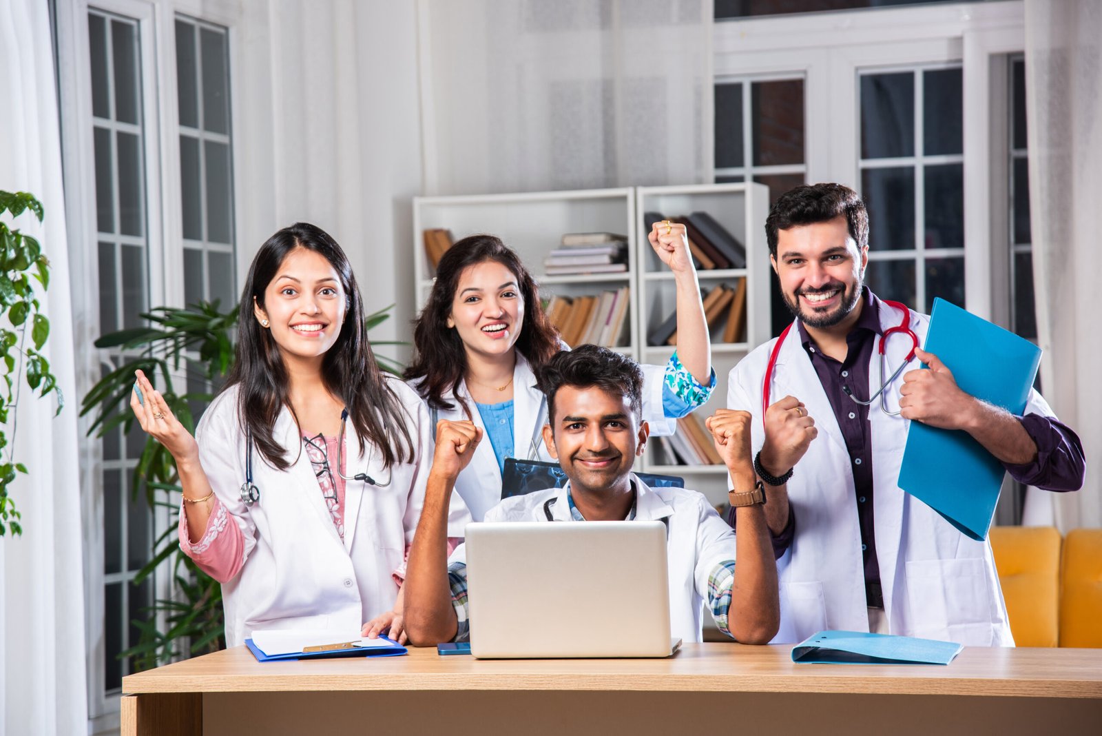Successful Young Indian asian medical doctors are using a laptop and smiling while having a discussion at table